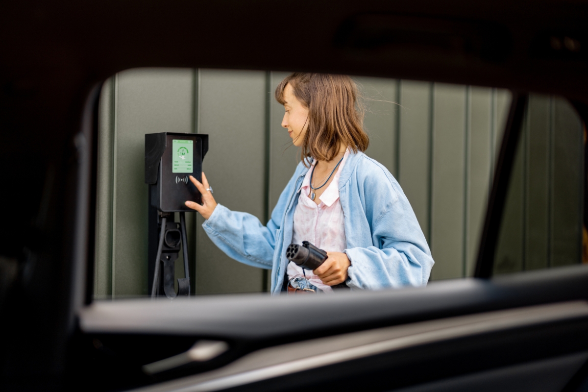 devojka sprema punjač za punjenje električnog automobila