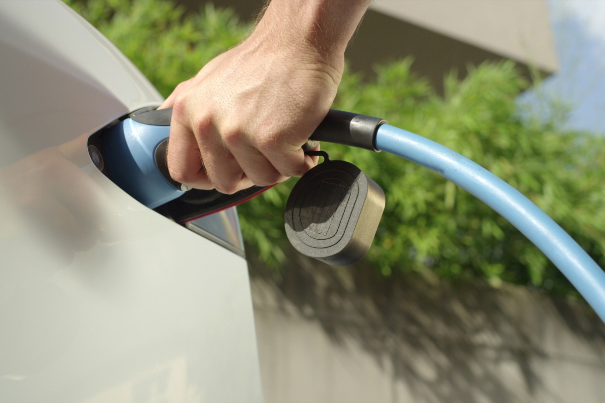 prikaz osobe koja stavlja električni automobil na punjenje