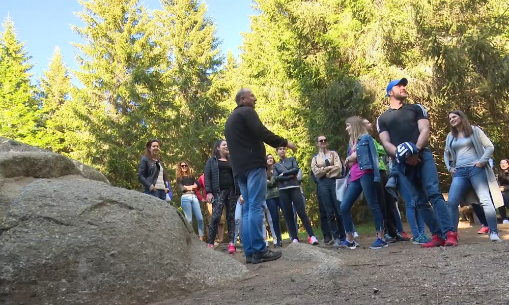Grupa kolega okupljena u šumi tokom organizovane team building aktivnosti u prirodi.